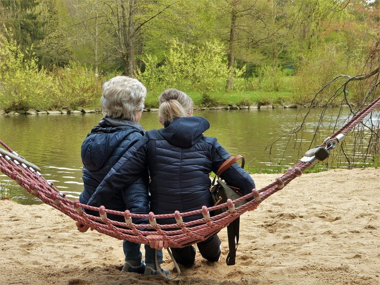 a group of people sitting on a bench in front of a river