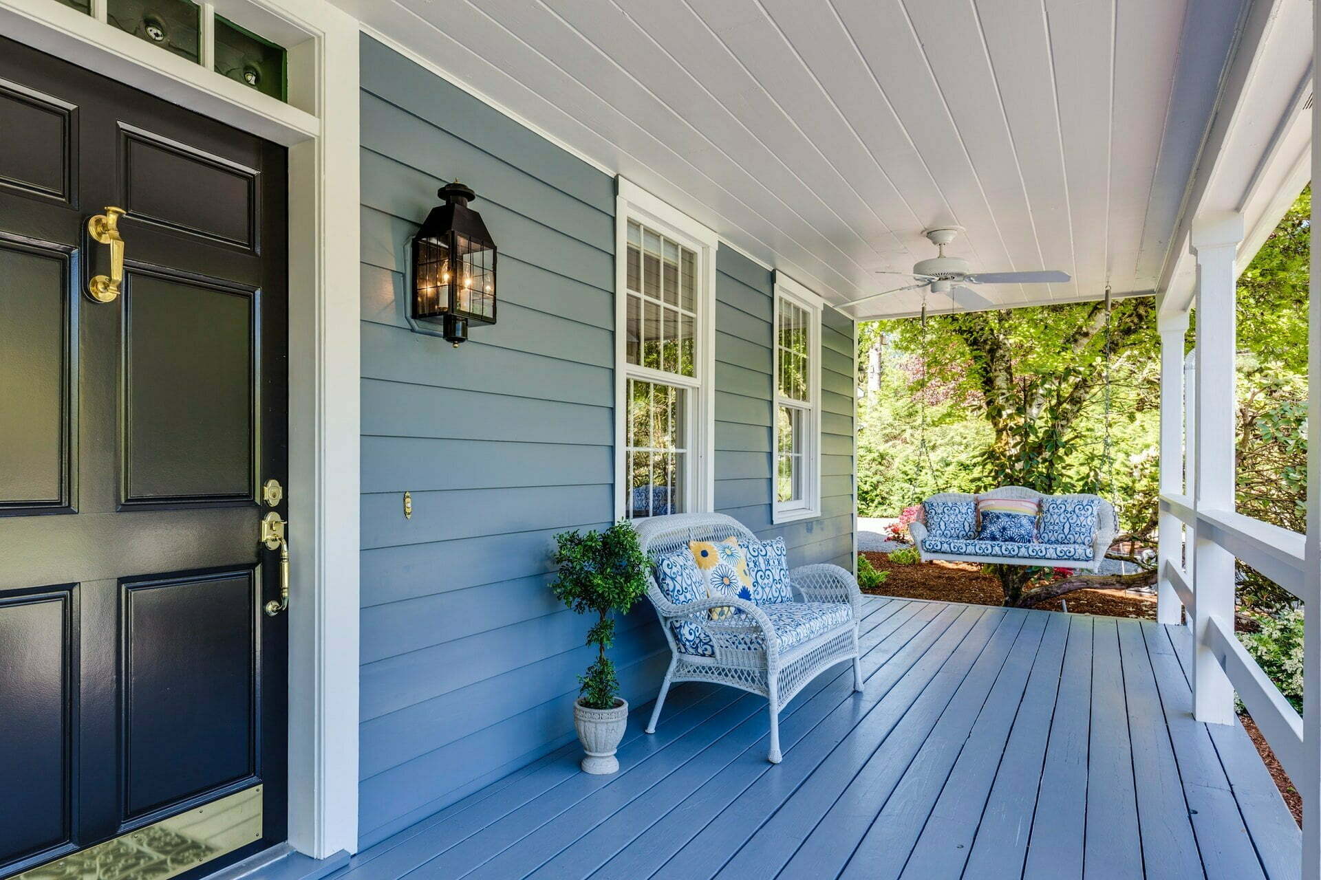 a porch with a chair and a table and a plant on the porch